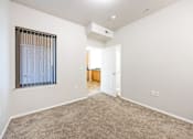 Thumbnail 11 of 23 - A room with a carpeted floor and a window with blinds.