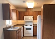 Thumbnail 3 of 3 - A kitchen with a white refrigerator and wooden cabinets.