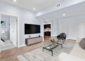 Thumbnail 20 of 45 - A modern living room with a white couch, a black chair, and a glass coffee table.