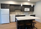 Thumbnail 5 of 33 - A kitchen with a white fridge and black cabinets.