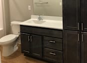 Thumbnail 7 of 33 - A bathroom with a toilet, sink, and cabinets.