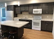Thumbnail 8 of 33 - A kitchen with a white counter top and black cabinets.