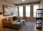 Thumbnail 11 of 33 - A living room with a green couch, a chair, and a painting on the wall.