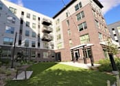 Thumbnail 28 of 33 - A modern building with a green lawn in front.