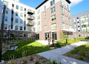 Thumbnail 32 of 33 - A modern building complex with a grassy area in front.