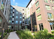 Thumbnail 33 of 33 - A modern building with a walkway between it and a grassy area.