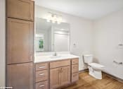 Thumbnail 6 of 51 - A bathroom with a toilet, sink, and wooden cabinets.