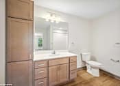 Thumbnail 16 of 40 - A bathroom with a toilet, sink, and mirror.