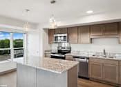 Thumbnail 21 of 40 - A kitchen with a granite countertop and stainless steel appliances.