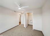 Thumbnail 26 of 40 - A room with a ceiling fan and carpeted floor.