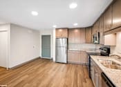 Thumbnail 29 of 40 - A kitchen with wooden floors and a stainless steel refrigerator.
