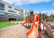 Thumbnail 33 of 40 - A playground with a red slide and a green roofed structure.
