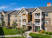 Thumbnail 21 of 26 - A large apartment complex with a well-maintained lawn and landscaping.