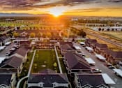 Thumbnail 27 of 28 - A sunset view of a residential neighborhood with houses and parked cars.