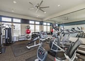 Thumbnail 24 of 37 - A gym with a variety of equipment including treadmills, weights, and a ceiling fan.