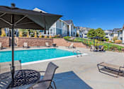 Thumbnail 4 of 37 - A pool area with a table and chairs and umbrella.