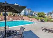Thumbnail 7 of 37 - A black umbrella is on a table next to a pool.