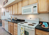 Thumbnail 17 of 29 - A kitchen with a white stove and wooden cabinets.