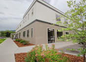 Thumbnail 2 of 29 - A modern building with a grey and white exterior and a landscaped front yard.