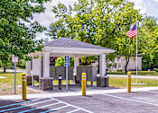 Thumbnail 23 of 33 - A gazebo is surrounded by a parking lot with a flag flying in the background.