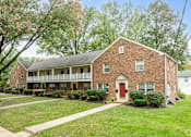 Thumbnail 4 of 12 - A red brick house with a white door and windows.