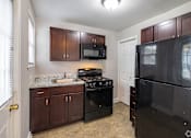 Thumbnail 6 of 12 - A kitchen with a black refrigerator and black stove.