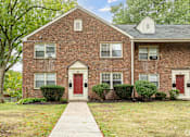 Thumbnail 2 of 12 - A brick house with a red door and a white door.