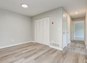 Thumbnail 14 of 41 - an empty room with a door to a closet and a hallway with wood flooring at Boulder Pointe Apartments in Middletown, NY 10940