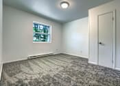 Thumbnail 10 of 17 - A room with a carpeted floor, a window, and a door.