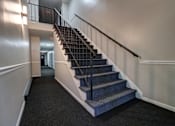 Thumbnail 14 of 17 - A staircase with a metal railing and a carpeted floor.