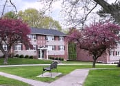 Thumbnail 2 of 38 - a bench sits in the middle of a grassy area in front of a brick building