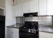 Thumbnail 4 of 23 - a kitchen with white cabinets and a black stove