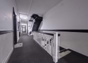 Thumbnail 19 of 23 - a long hallway with stairs and white walls and a black staircase