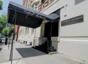 Thumbnail 2 of 23 - a building with a black awning on a sidewalk