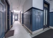 Thumbnail 18 of 23 - a hallway with blue doors and white walls and a tiled floor