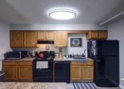Thumbnail 12 of 45 - Kitchen with black appliances and wooden cabinets at Cedar Park Apartments, Troy, NY