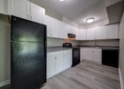 Thumbnail 5 of 28 - A black fridge in a kitchen with white cabinets.