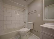 Thumbnail 13 of 55 - A white toilet sits in a white tiled bathroom.