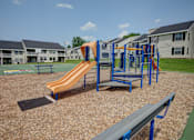 Thumbnail 42 of 55 - A playground with a slide, monkey bars, and a bench.