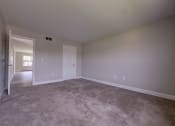 Thumbnail 18 of 47 - an empty living room with carpet and a door to a bedroom