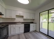 Thumbnail 7 of 47 - a kitchen with white cabinets and a sliding glass door to a balcony