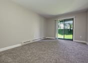 Thumbnail 14 of 34 - A room with a carpeted floor and a sliding glass door leading to a backyard.