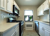 Thumbnail 4 of 23 - A kitchen with black appliances and white cabinets.
