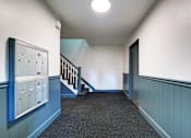 Thumbnail 15 of 23 - A hallway with a staircase and mailboxes on the wall.