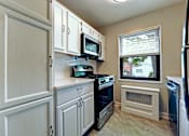 Thumbnail 5 of 23 - A small kitchen with white cabinets and appliances.