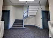 Thumbnail 8 of 10 - A staircase with a metal railing and steps leading up to a door.