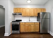 Thumbnail 3 of 10 - A kitchen with wooden cabinets and a stainless steel refrigerator.