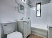 Thumbnail 4 of 10 - A white toilet sits next to a sink in a small bathroom.