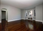Thumbnail 6 of 10 - A room with wooden floors and white walls.