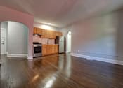 Thumbnail 5 of 10 - A kitchen with wooden floors and a pink wall.
